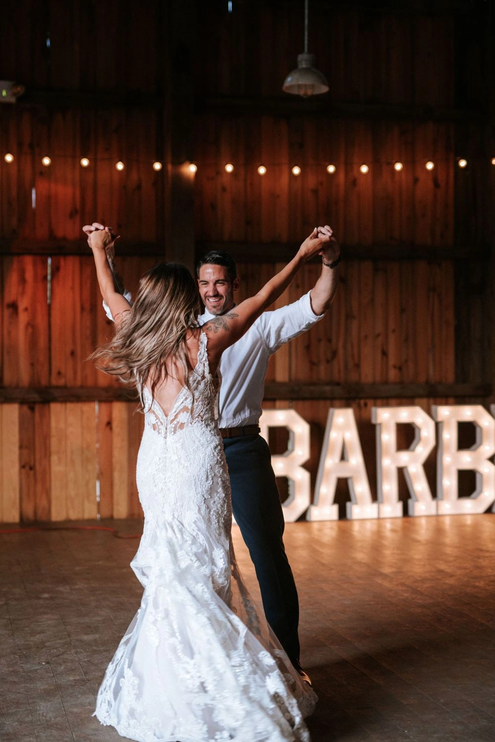 Newlyweds dancing together beneath warm reception lights
